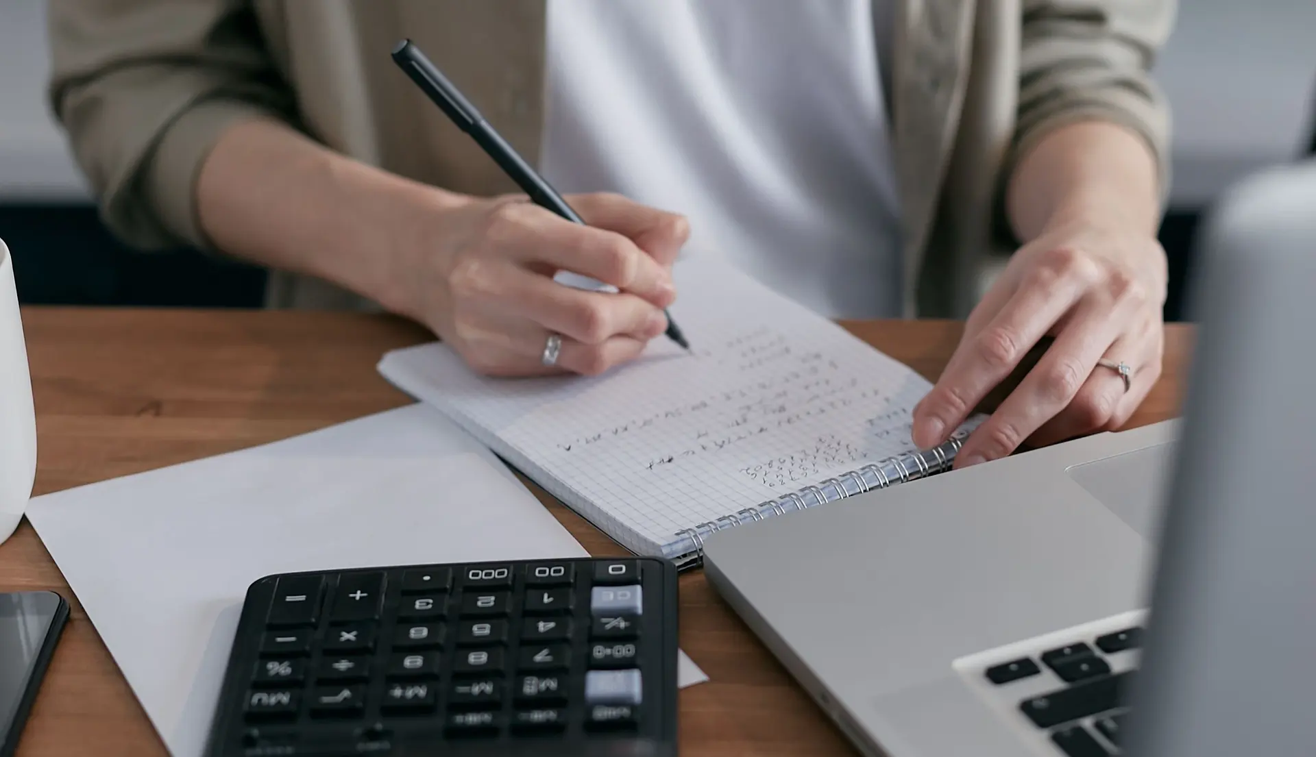 Accountant using a calculator and notebook to prepare business closing balances